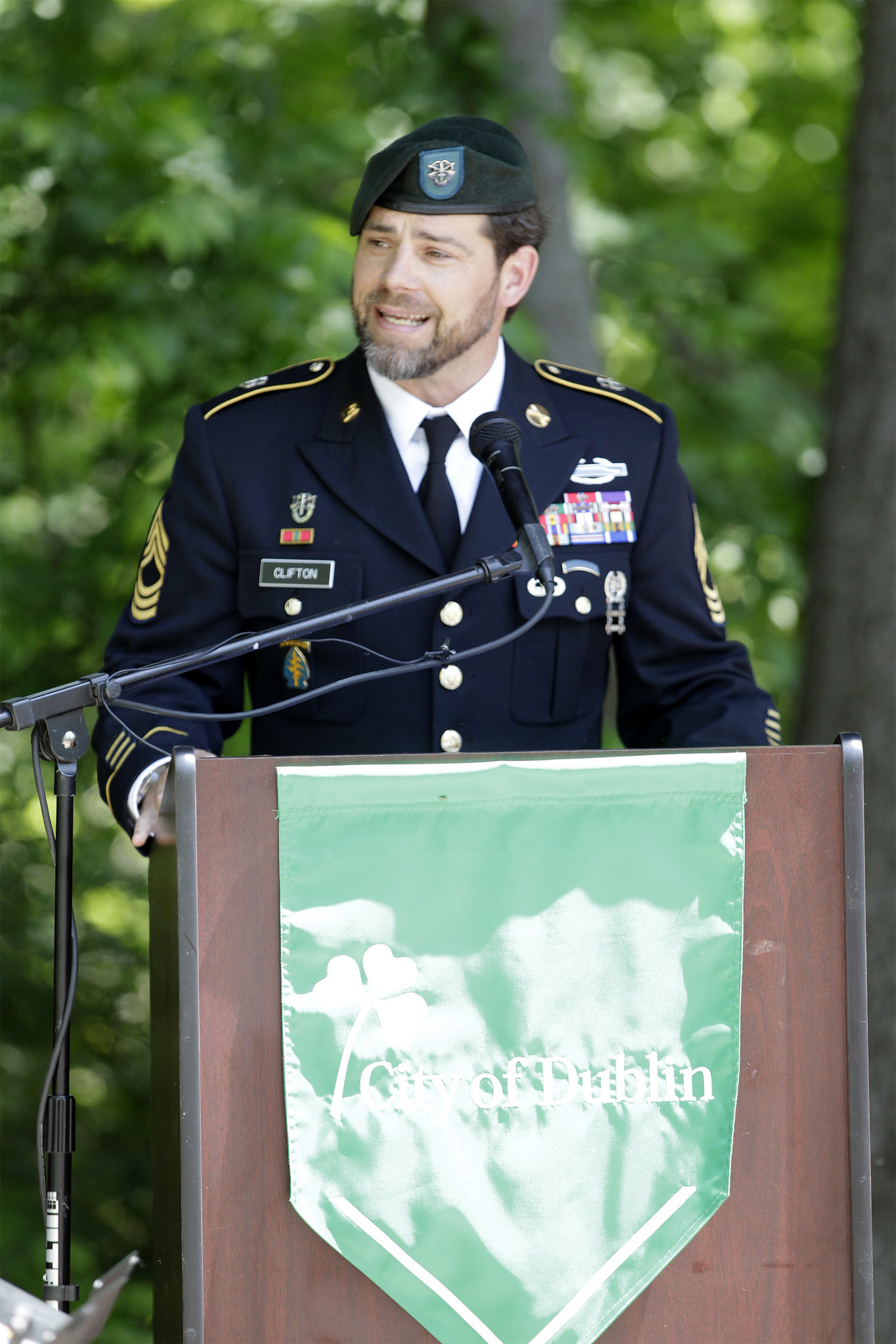 Sean Clifton in Army dress uniform and green beret, speaking at a podium